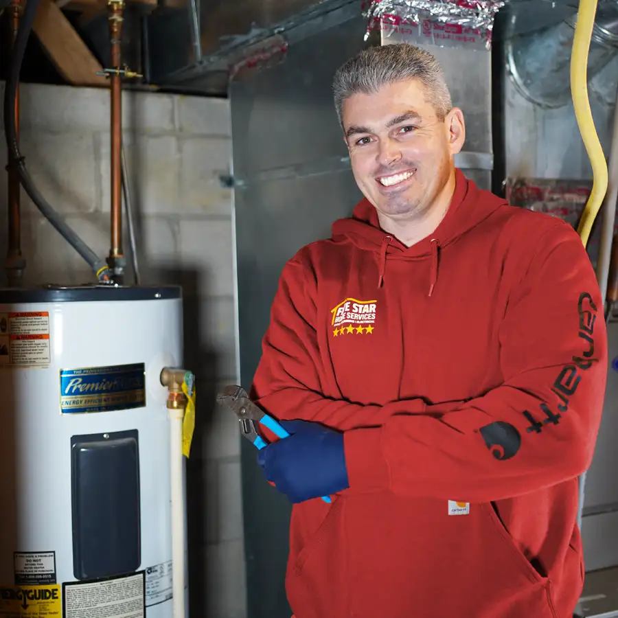 Plumber holding a wrench standing next to a water heater