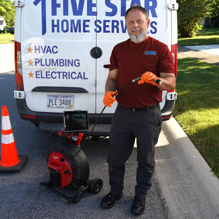 Plumber holding video camera inspection equipment standing behind a five star van