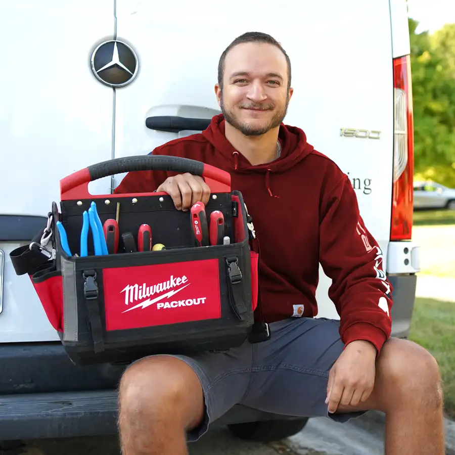 Plumber with tools sitting on a van bumper