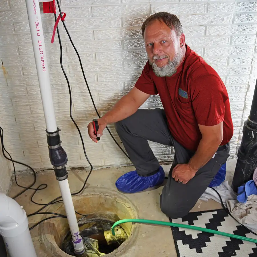 plumber holding a flashlight inspecting a sump pump